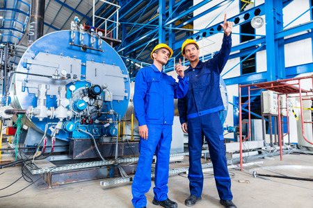 Worker in Asian manufacturing plant discussing in front of machines