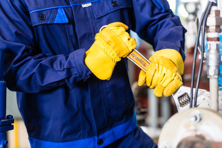 Technician in factory at machine maintenance working with wrenchの写真素材