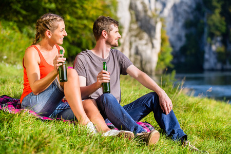 Man and woman having break hiking at riverの写真素材