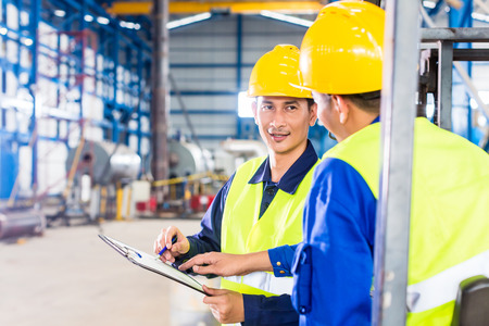 Worker and forklift driver in industrial factory looking at camera