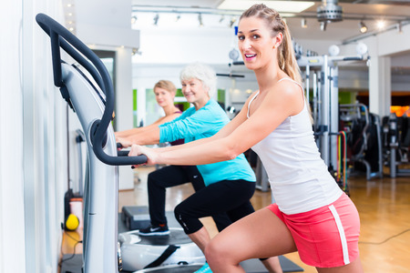 Group of people on vibrating plates in gym training