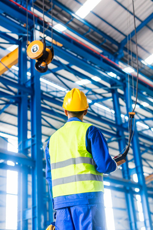 Worker in factory controlling crane with remoteの写真素材