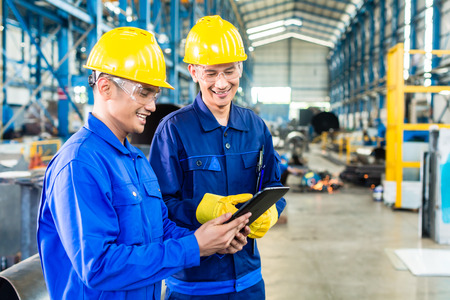 Two workers in production plant as team discussing, industrial scene in background Two workers in production plant as team discussing, industrial scene in background