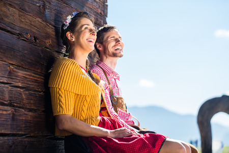 Couple in traditional clothing front of mountain hut marveling at the sceneryの写真素材