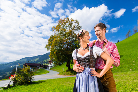 Couple in traditional Tracht standing on meadow in alp mountainsの写真素材