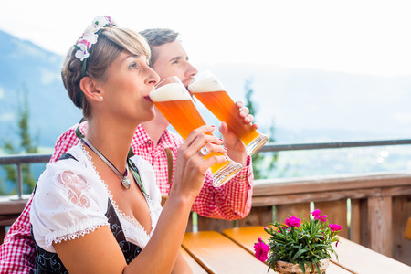 Couple on mountain hut drinking wheat beer, in the background alpine sceneryの写真素材