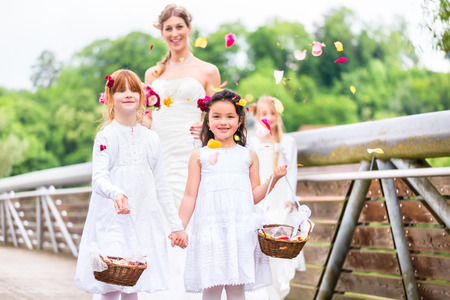 Wedding couple bride and groom with flower children or bridesmaid in white dress and flower basketsの写真素材