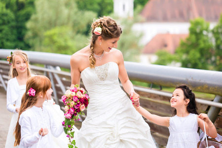 Wedding couple bride and groom with flower children or bridesmaid in white dress and flower basketsの写真素材
