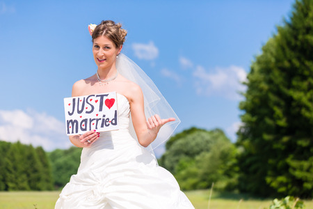 Wedding bride standing hitchhike at street with "just married" signの写真素材