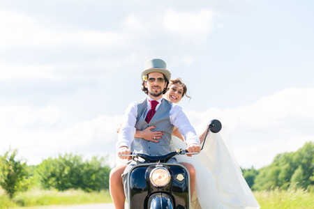 Wedding groom and bride driving motor scooter having funの写真素材
