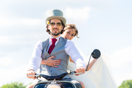 Wedding groom and bride driving motor scooter having funの写真素材