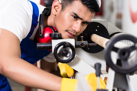 Worker adjusting turning machine in factory preparing the manufacturing processの写真素材