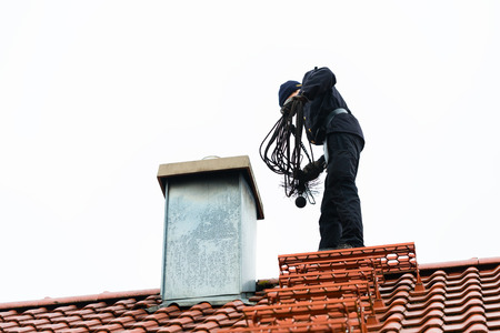 Chimney sweep standing on roof of home workingの写真素材