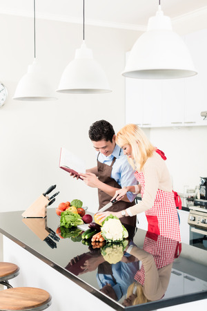 Asian couple cooking in stylish and modern kitchenの写真素材