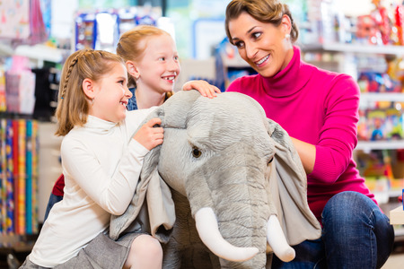 family in toy store cuddling with stuffed animal, mother with two daughtersの写真素材