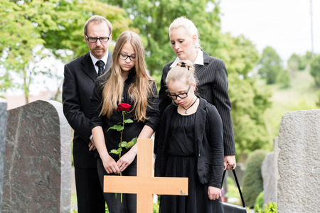 Family mourning at grave on graveyard or cemeteryの写真素材