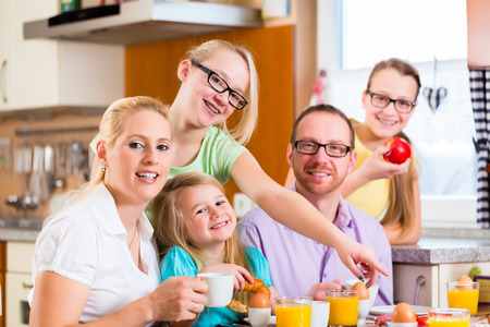 Family having joint breakfast in kitchen eating and drinkingの写真素材