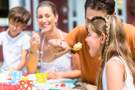 Family with cake in summer gardenの写真素材