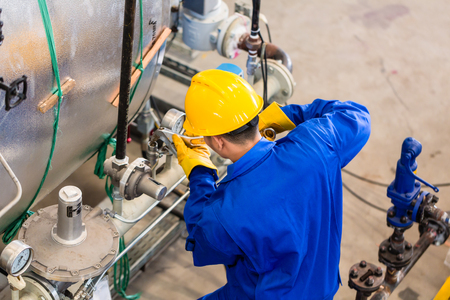 Technician in factory at machine maintenance working with wrench, top view on the man