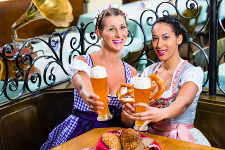 Girlfriends with Pretzel and Beer in Bavarian Inn eating and drinkingの写真素材