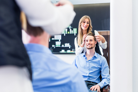 Haircutter cutting hair, shot in mirrorの写真素材