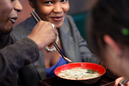 Friends, black and Latin people, eating ramen noodle soup in Japanese Restaurant