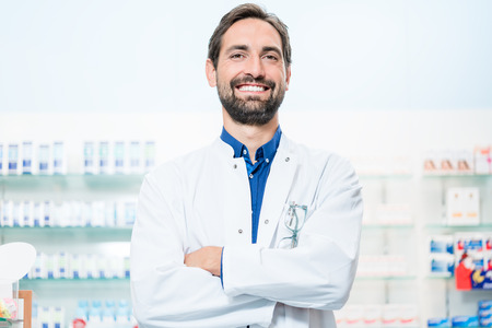 Apothecary in pharmacy standing at shelf with drugsの写真素材