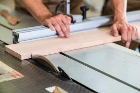 Carpenter cutting wooden board with circular sawの写真素材