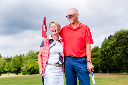 Senior couple playing golf standing on greenの写真素材