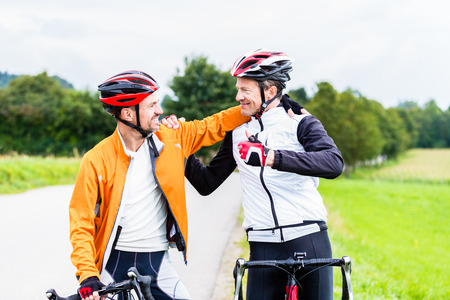 Bicyclists doing fitness sport embrace each other in finish, celebrate victory