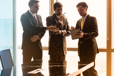 Asian business people having conversation in front of window in conference room, filtered imageの写真素材