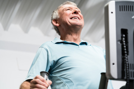 Elderly man training on cross trainer at the gymの写真素材