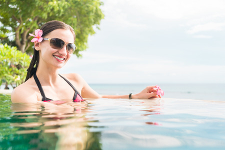 Woman in summer vacation relaxing swimming in pool with the ocean in the backgroundの写真素材