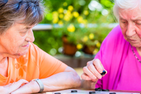Two senior ladies playing board game in rest homeの写真素材