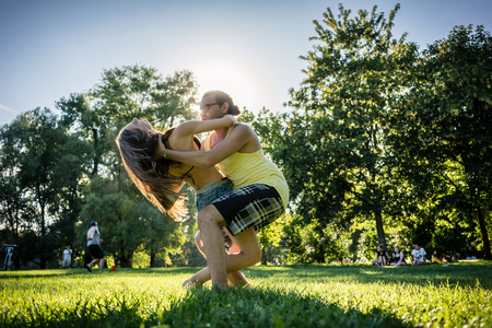 Couple dancing bachata in park backlit training dip figureの写真素材
