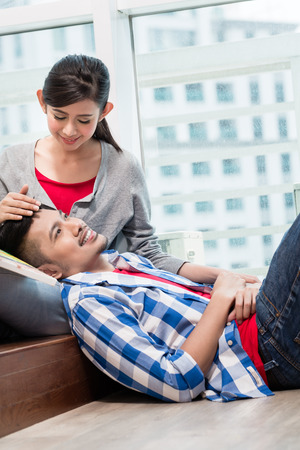Asian girl caressing her boyfriend lying exhausted on the groundの写真素材