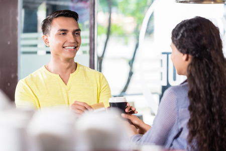 Indian man customer paying for takeaway coffee with credit card  の写真素材