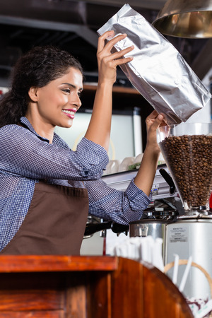Barista in Indian cafe filling coffee grinder with coffee beansの写真素材
