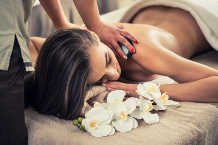 Young woman enjoying the therapeutic effects of a traditional hot stone massage at luxury spa and wellness centerの写真素材