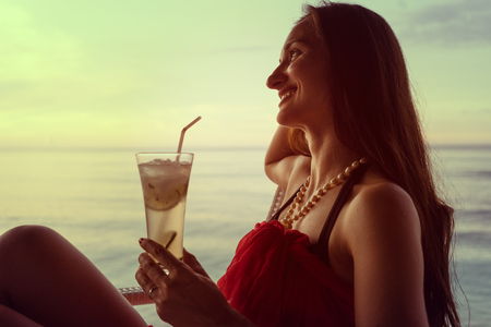 Woman tourist in summer vacation drinking cocktail at sunsetの写真素材