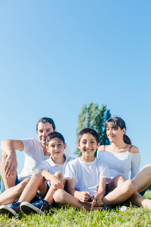 family dressed in white in park in summer sitting in meadowの写真素材