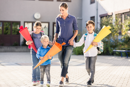 Mum and children with paper funnels for candy after first day at schoolの写真素材
