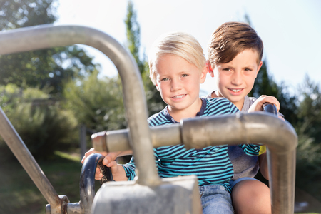 Two boys using digger on adventure playground in park having funの写真素材