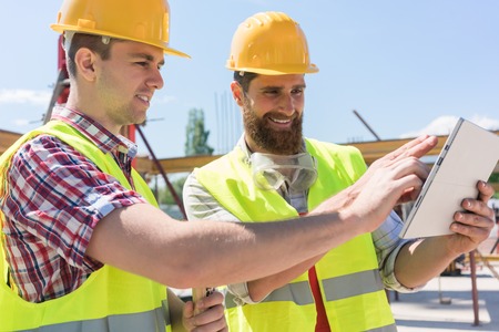 Two young workers watching a video with useful information or communicating online through a tablet...