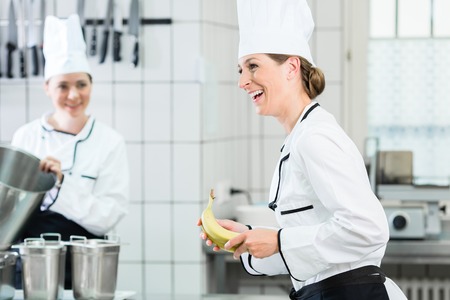 Two female chefs in gastronomic kitchen wearing white cooking uniformsの写真素材