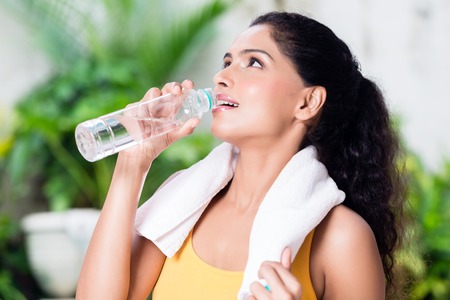 Portrait of healthy young woman drinking plain water during workout outdoors