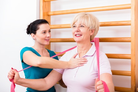 Senior patient doing therapeutic rehabilitation exercises at gymnasium ladderの写真素材
