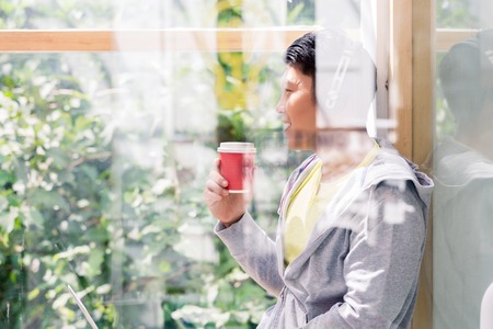 Young man day dreaming while drinking a coffee during break in the office or at the universityの写真素材