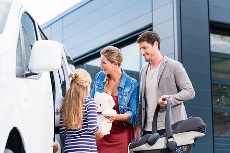 Family checking new car in car dealership with child seatの写真素材