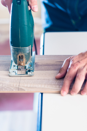 DIY worker cutting wooden panel with jig sawの写真素材